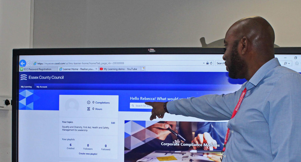 Man pointing to a television with the Essex Council Learning website on the screen