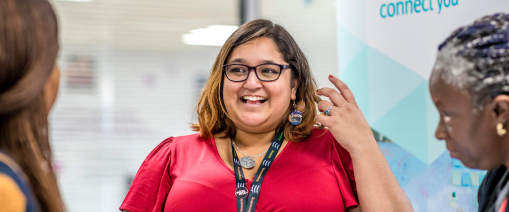 A woman smiling while speaking with two other women.