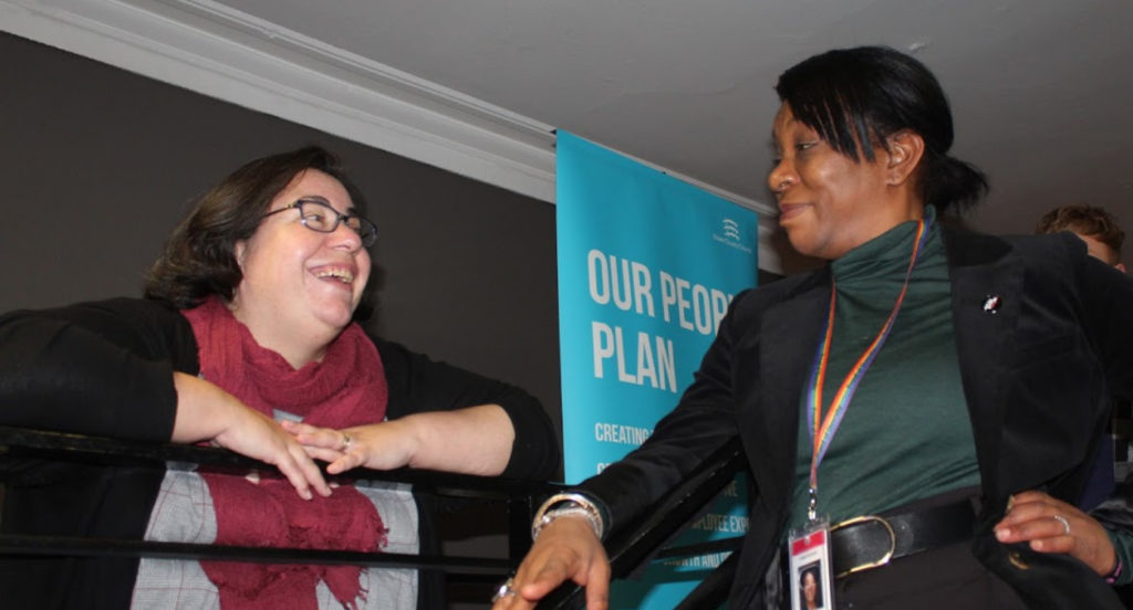 Two women smiling during a conversation.